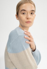 Strickpullover in Hellblau und Beige, mit einem strukturierten Muster und weiten Ärmeln. Einfaches Design mit lockerer Passform.