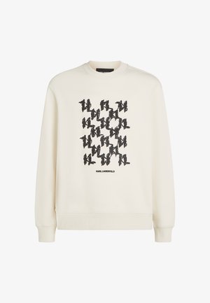 Kremowy sweter z nadrukiem w czarnym kolorze, powtarzającym się wzorze oraz napisem "KARL LAGERFELD" na dole. Miękka faktura, ściągacze na rękawach.