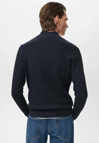 Pulover navy cu nervuri, cu guler, mâneci lungi și talie ajustată. Purtați-l cu blugi blau, evidențiind detalii de design minimaliste.