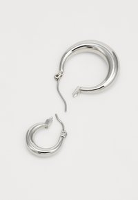Silver hoop earrings, one large and one small. They have a smooth, polished surface and a contemporary design with a secure clasp.