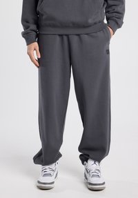 Grijze katoenen sweatpants met een elastische tailleband en zijzakken, met een losse pasvorm en een klein logoplaatje aan de linkerzijde.
