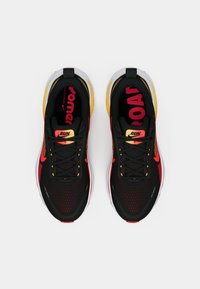 Μαύρα αθλητικά παπούτσια με κόκκινες και κίτρινες λεπτομέρειες. Δίκτυο επάνω μέρος, επενδεδυμένος γιακάς και μαξιλαρωμένη σόλα. Εντυπωσιακό κείμενο "RUN" στις σόλες.