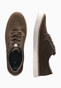 Brown canvas sneakers with a white rubber sole, featuring round laces, metal eyelets, and a subtle logo on the tongue.