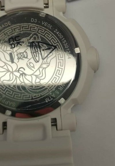 Reloj de pulsera analógico blanco con caja redonda, diseño grabado de un rostro en el cristal y resistencia al agua de 5 ATM.