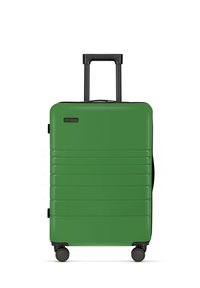 Groene harde koffer met een geribd ontwerp, zwarte uitschuifbare handgreep en vier wielen voor stabiliteit en mobiliteit.