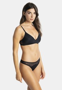 Ensemble de lingerie noire comprenant un soutien-gorge lisse et moulé avec des bretelles fines et une culotte échancrée avec un détail en dentelle transparente.