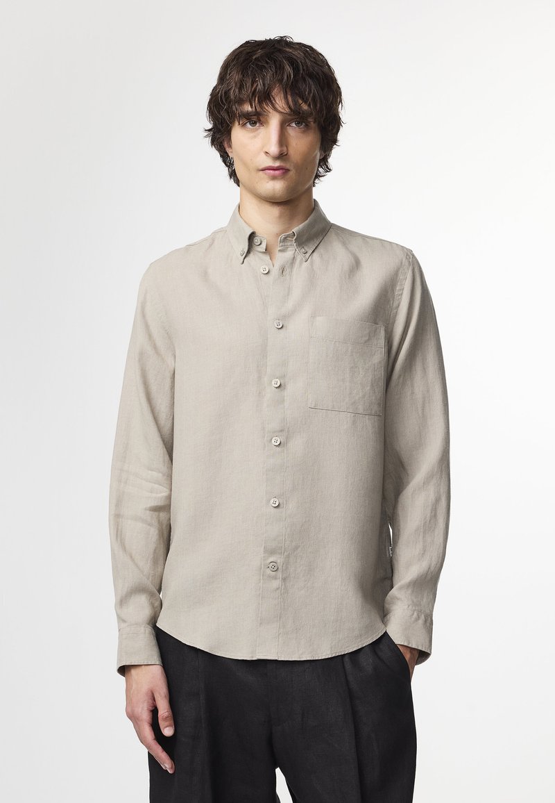 Light beige button-up shirt made of linen with a chest pocket, collar, and long sleeves, featuring a straight hem and subtle texture.