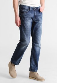 Ljusblå denimjeans med en lös passform, utrustade med fem fickor och dragkedja. Kombinerat med beige ankelboots för en avslappnad look.