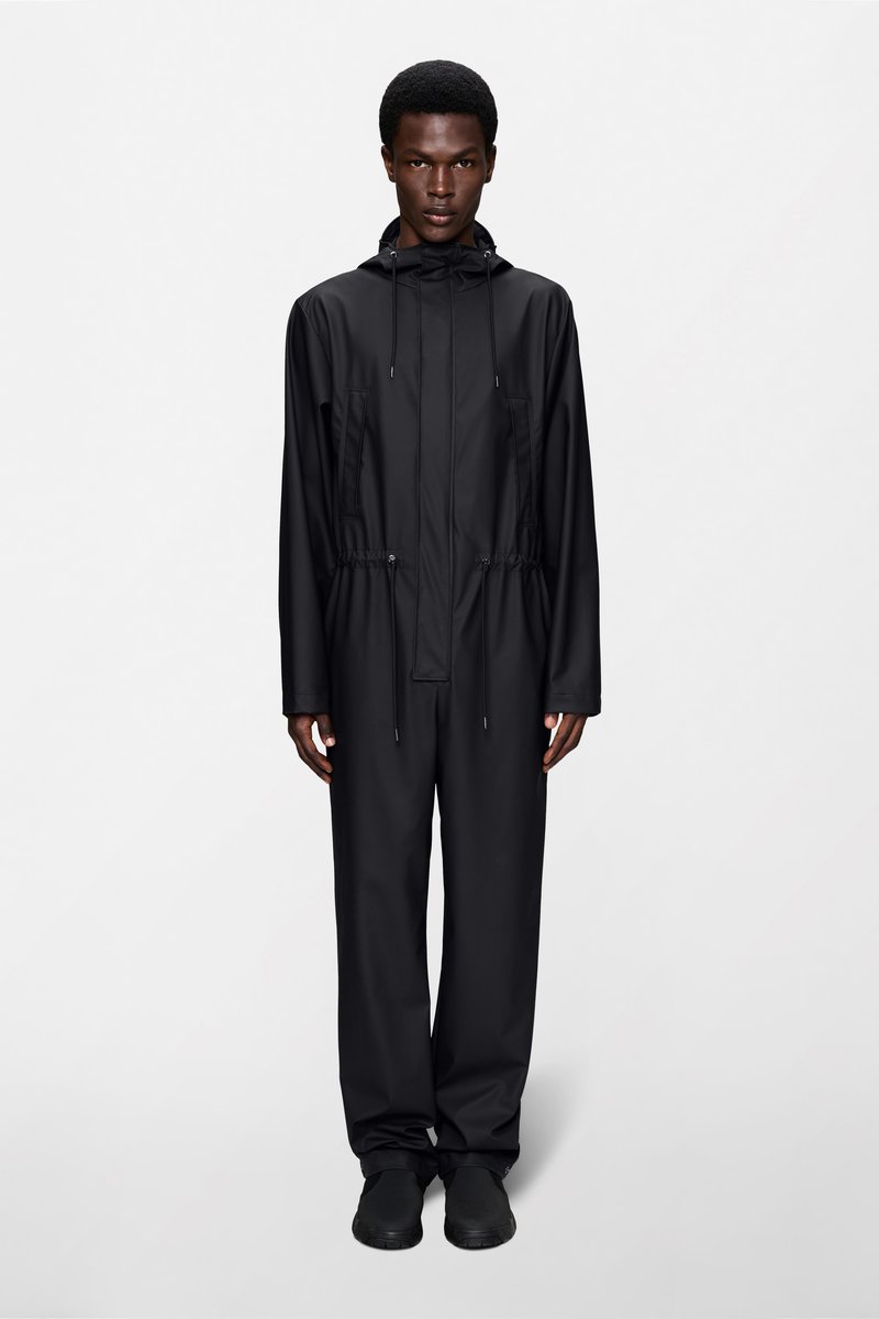 Must, kergekaaluline, veekindel kombinesoon kapuutsiga, elastsete mansettide ja nöörvöökohaga. Minimalistlik disain, sile tekstuur ja nähtamatud kinnitusdetailid.