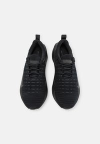 Zwarte sport sneakers met een gestructureerde bovenkant, vetersluiting en trekhaken. Heeft een gladde zool en een grijs Nike-logo.