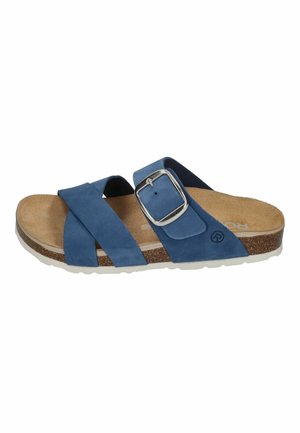 Blauwe suède slide sandaal met twee overlappende banden, een zilveren gespaccent, en een kurken voetbed op een witte rubberen zool.