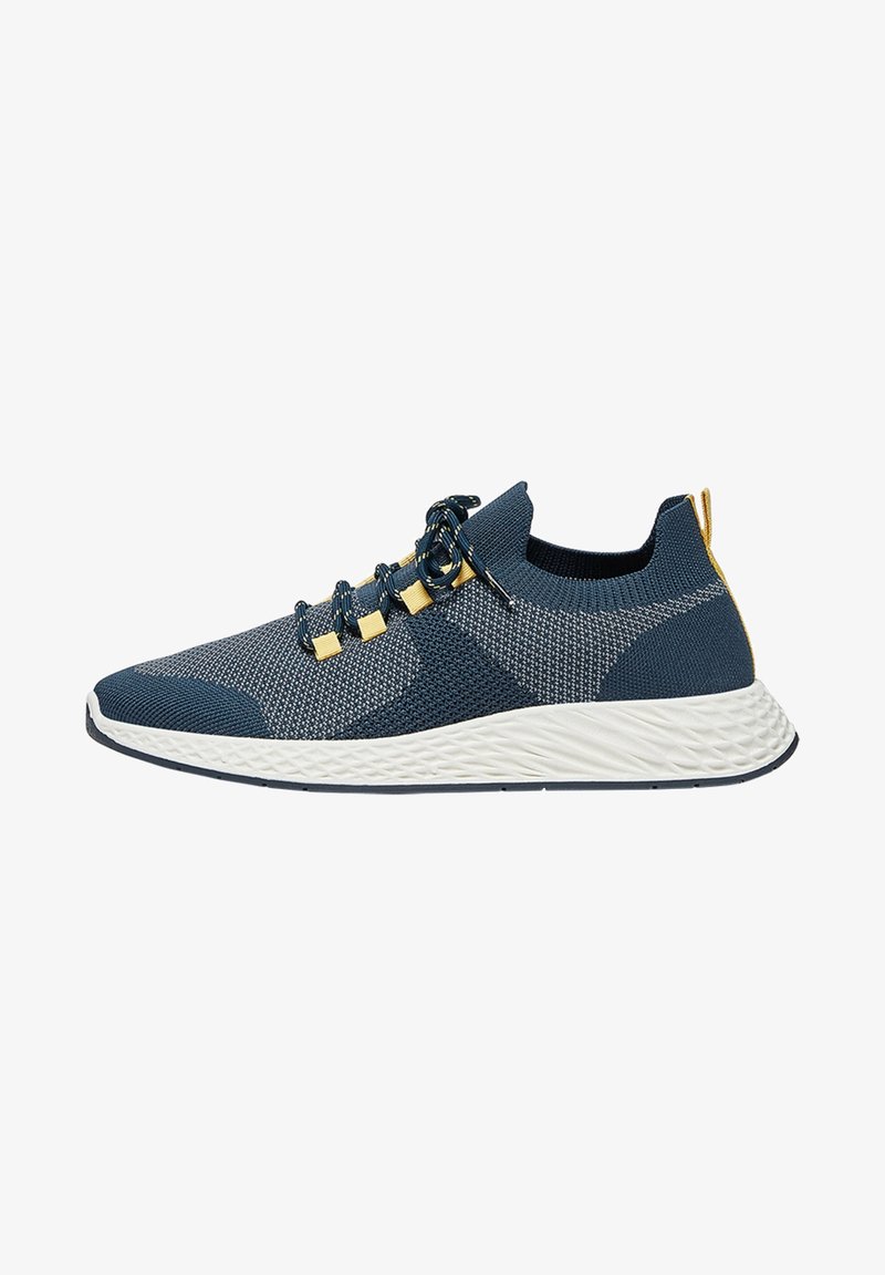 Baskets tricotées bleu foncé et gris avec semelle blanche texturée, lacets noirs et jaunes, et languette de talon jaune, vue de côté.