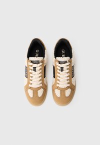 Sneakers in suede marrone con accenti in finto pelliccia color crema, pannelli neri a contrasto, lacci beige e suole imbottite per il comfort.