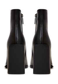 Black ankle boots with a smooth leather exterior, high block heels, side zipper closures, and minimalistic design.