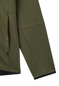 Indumento verde oliva a maniche lunghe con vestibilità rilassata. Presenta una texture morbida, fessure laterali e accenti neri sull'orlo e sui polsini.