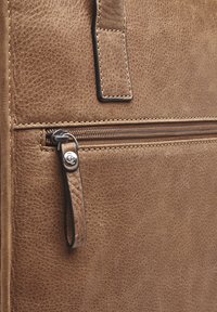 Braune Lederhandtasche mit strukturiertem Finish, ausgestattet mit einer Reißverschlusstasche und einem Leder-Zieher. Subtile Nähte betonen das Design.