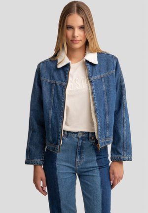 Denim jakk, millel on valge fliisist krae, tõmblukuga sulgemine ja pika varrukaga. Hele ja tume sinine toon koos tekstureeritud kangaga ja õmblusdetailidega.