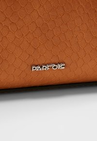 Brun tekstureret håndtaske med et slangeskinds mønster, der har et sølvfarget "PARFOIS"-logo på forsiden og en mørk kant langs kanterne.