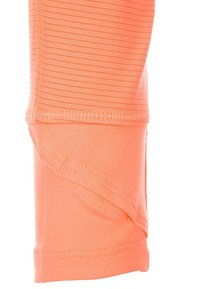 Leggings deportivos naranjas elásticos con textura acanalada, que presentan un diseño ajustado y costuras reforzadas en el dobladillo.