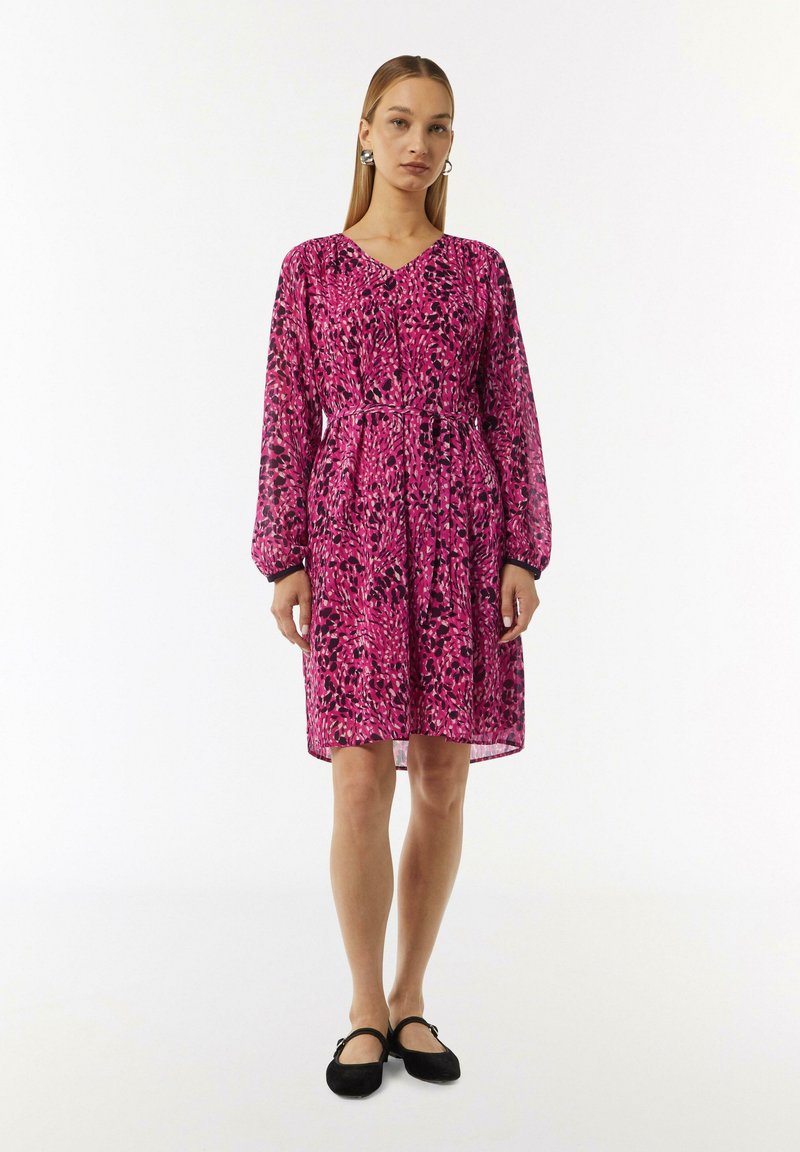 Rosa Blumenkleid mit langen Ärmeln und einem V-Ausschnitt, mit einer taillierten Taille und einem fließenden Rock. Schwarze Akzente an den Ärmeln.