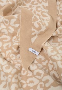 Beige huivi, jossa on hienovarainen eläinkuviollinen kuvio kermanvärisenä. Pehmeä tekstuuri, ja kulmassa näkyy etiketti, jossa lukee "CECIL".