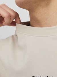 Beige sweatshirt met hoge kraag, zachte textuur en zichtbare logodetail aan de voorkant, die bij de hals wordt aangepast.