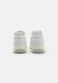 White sneakers with a smooth leather and suede upper, padded collar, and a textured beige sole. "LOVE MOSCHINO" embossed on the heel.