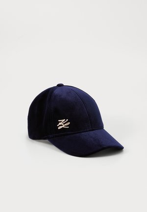 Navy velvet baseball cap with a curved brim, featuring an embroidered logo in a light color on the front panel. Soft texture and structured form.