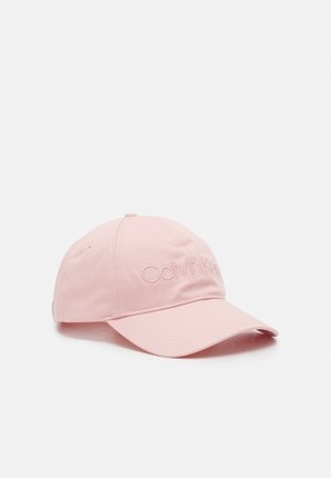 Lichtroze Calvin Klein baseballpet met gebogen klep en geborduurd logo aan de voorkant, tegen een effen witte achtergrond.