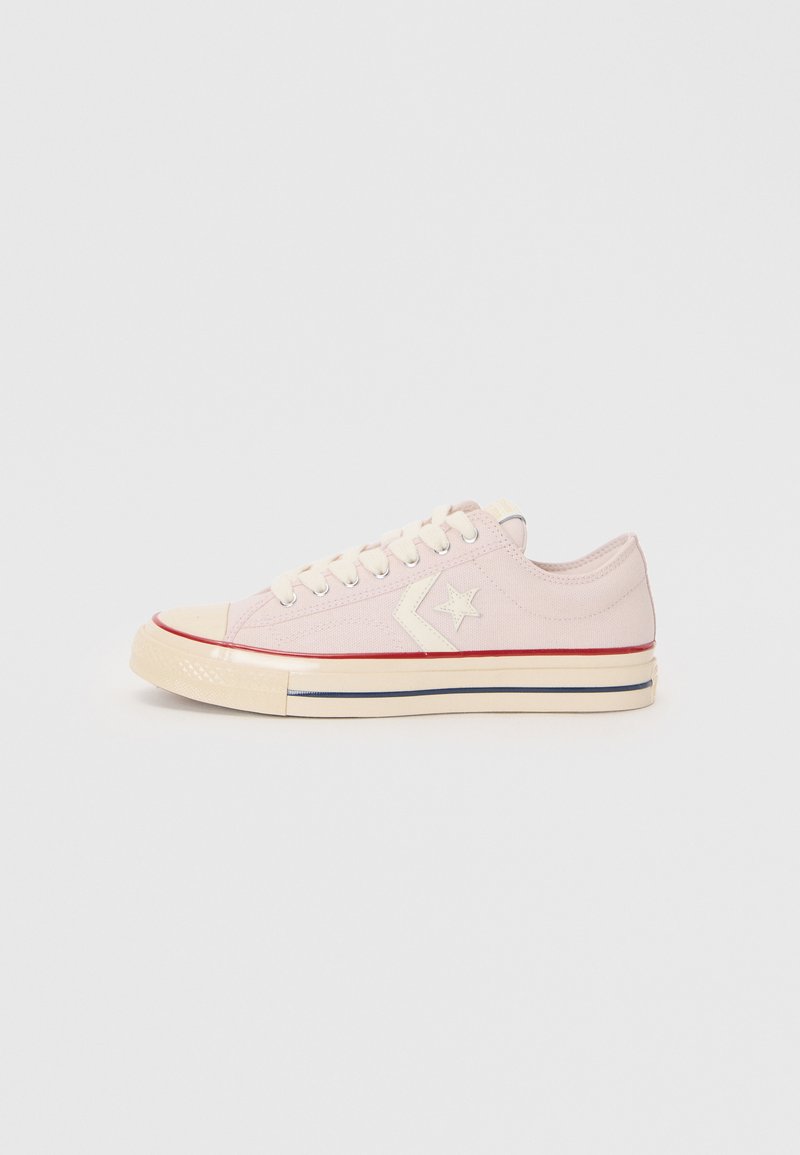 Sneaker in tela rosa con lacci crema e suola in gomma. Presenta un dettaglio a stella bianca, una striscia rossa vicino alla suola e un design classico a scarpa bassa.