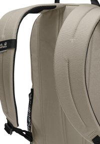 Sangles de sac à dos rembourrées beige avec un motif texturé, dotées d'un doublure en maille noire et de clips ajustables pour un maintien sûr.