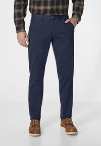 Marineblaue Hosen mit geradem Schnitt, aus leichtem Stoff. Mit einem Knopfverschluss, Taschen und kombiniert mit braunen Stiefeln.