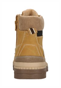 Bruna ankelboots med en strukturerad stickad krage, sidoglid, och kontrasterande bruna detaljer. Har en hållbar gummisula och sömnadsdetaljer.