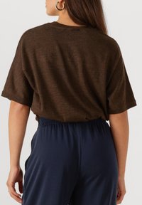 Bruine oversized t-shirt met een ronde halslijn, korte mouwen en een zachte textuur, gecombineerd met marineblauwe broek met elastische tailleband.