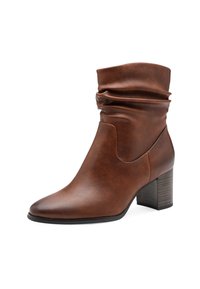 Botte-cheville en cuir marron avec une tige ample, un bout pointu et un talon empilé. Texture lisse avec des détails de couture minimalistes.