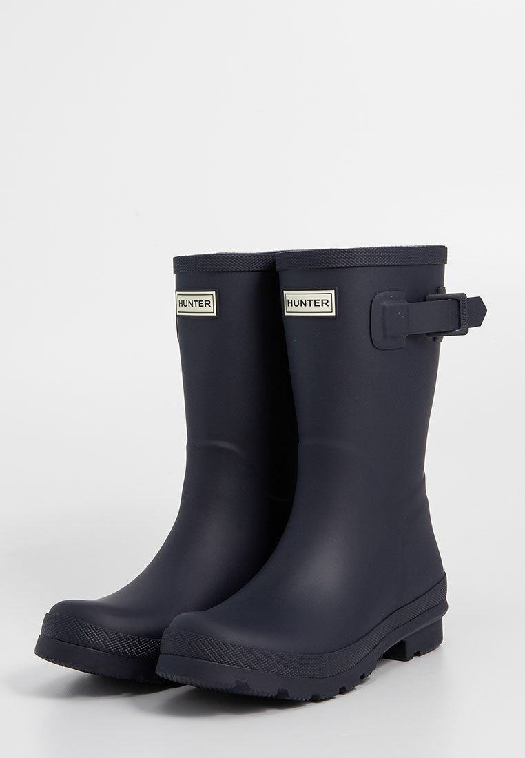 Botas de lluvia de goma en color navy con acabado mate, punta redondeada, correa ajustable y detalle de hebilla, y suela texturizada para un mejor agarre.