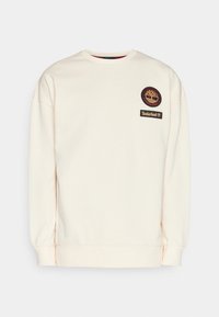 Sudadera de color beige claro hecha de una tela suave. Presenta puños y cuello acanalados, con el logotipo de Timberland bordado y un parche en el pecho.
