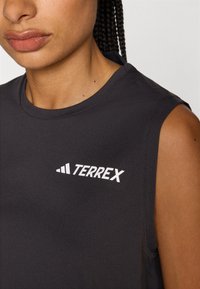 Svart ermeløs topp laget av glatt stoff, med en hvit "TERREX" logo på forsiden. Enkel design med rund hals og armhull.