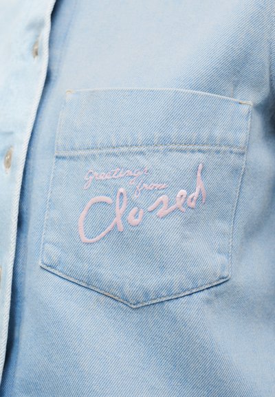 Γαλάζιο πουκάμισο από τζιν με τσέπη στο στήθος που φέρει ροζ κεντημένο κείμενο με τη φράση «greetings from Closed». Κανονικός γιακάς πουκάμισου και κουμπιά.