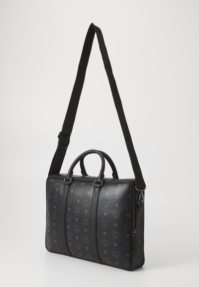 Black leather briefcase with textured surface, featuring a zip closure, dual top handles, and an adjustable strap with logo detailing.