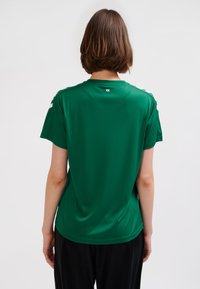Green athletic t-shirt made of soft fabric, featuring short sleeves and a round neckline. White accents are visible on the shoulders.