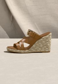 Sandale compensée en cuir marron avec semelle plateforme en jute tressé et bride à boucle dorée, présentée de profil sur fond neutre.