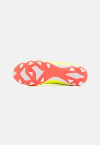 Sole di scarpa sportiva gialla con accenti rosa. Presenta un motivo testurizzato per una migliore aderenza e dettagli bianchi, inclusi tacchetti triangolari per la trazione.