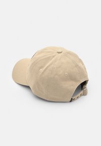 Cappello da baseball in cotone beige con visiera curva, tessuto testurizzato e cinturino regolabile con accenti a motivo stellato.