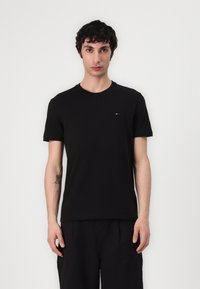 Tricou negru cu mânecă scurtă din bumbac moale, cu guler rotund și un logo mic colorat pe piept. Croială clasică.