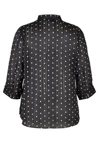 Camicia nera trasparente con righe verticali e pois bianchi. Presenta maniche con polsini e colletto a bottoni sul retro. Texture liscia.