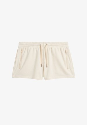 Beige short met trekkoord, elastische tailleband en twee verticale ritszakken aan de voorkant, gemaakt van zachte stof.