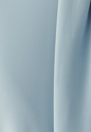 Gaiši zils audums ar gludu tekstūru un smalku ribveida rakstu, kas atspoguļo mīkstas locījumu un krituma līnijas. Nav redzamas aparatūras vai akcentu.