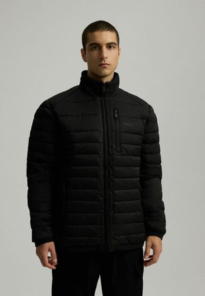 Czarna kurtka puchowa z pikowanymi sekcjami, wysokim kołnierzem i zamkiem z przodu. Posiada kieszeń na piersi z zamkiem oraz elegancki, minimalistyczny design.