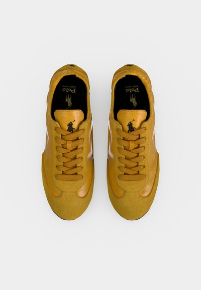 Paire de baskets jaunes Polo Ralph Lauren avec lacets et semelles intérieures noires avec le logo de la marque et un motif de cavalier, vues de dessus.